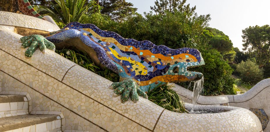 Mosaic dragon sculpture with vibrant colors, perched on a fountain in Park Guell, Barcelona.