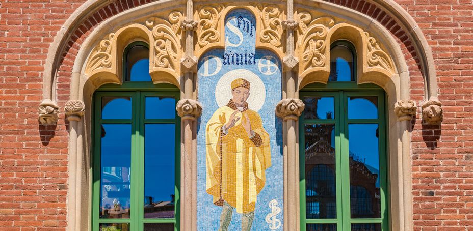 Entrance to the Recinte Modernista de Sant Pau featuring stained glass window with religious figure.