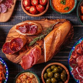 A colorful spread of Spanish tapas, bread, cured meats, and appetizers