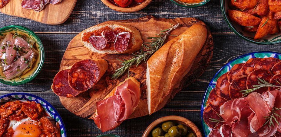 A colorful spread of Spanish tapas, bread, cured meats, and appetizers